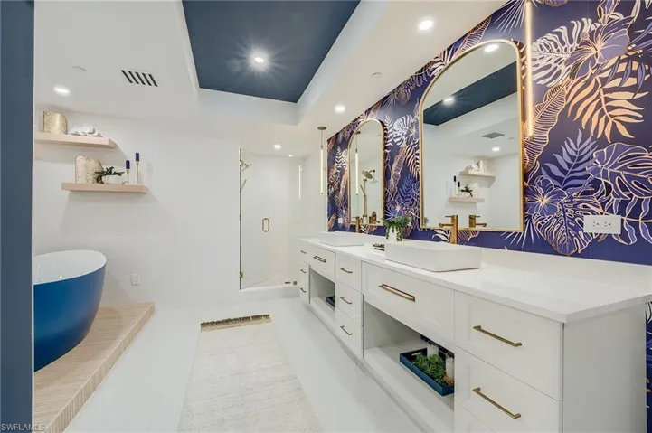 Bathroom with double vanity, a shower stall, a freestanding bath, recessed lighting, and a tray ceiling