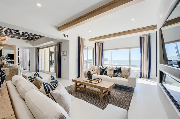 Living area with healthy amount of natural light, beam ceiling, recessed lighting, and light tile patterned floors