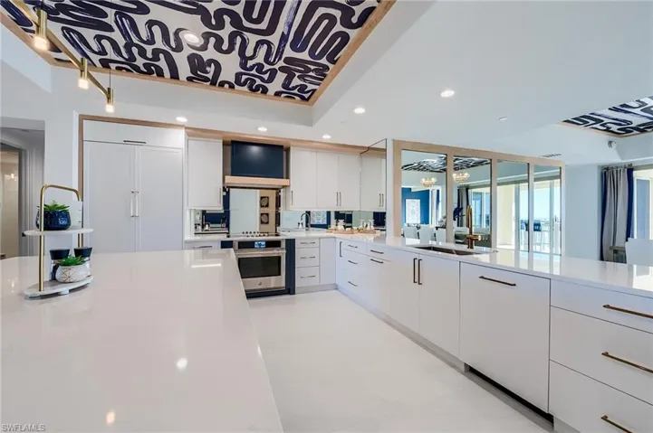Kitchen featuring stainless steel oven, a sink, light countertops, white cabinets, and recessed lighting