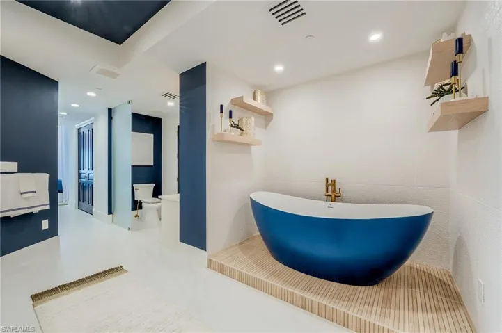 Bathroom featuring toilet, a freestanding tub, recessed lighting, and a sink