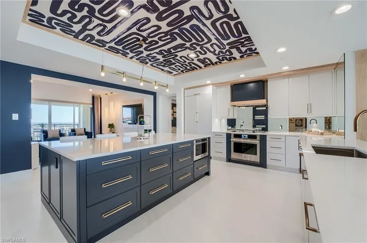 Kitchen with stainless steel oven, a sink, a tray ceiling, light countertops, and recessed lighting