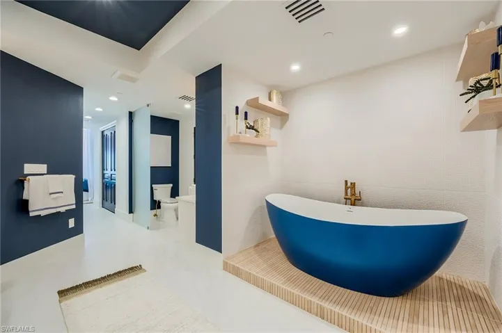 Full bathroom featuring toilet, a soaking tub, a sink, and recessed lighting