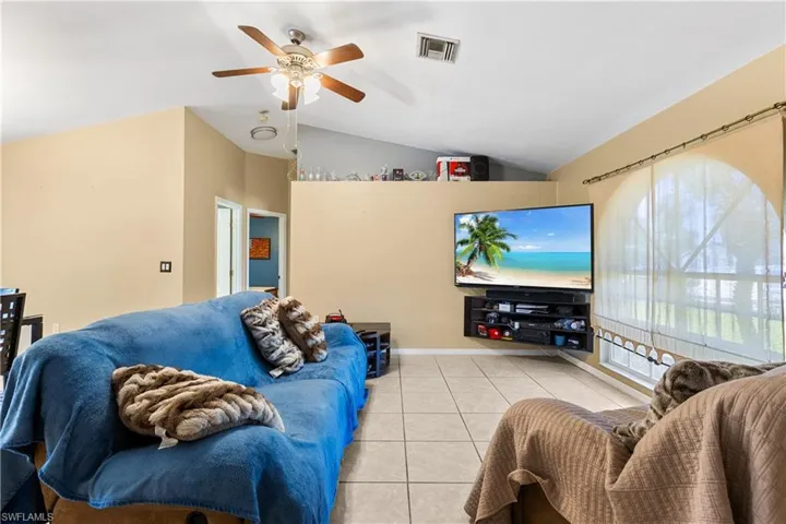 Tiled living room with ceiling fan and vaulted ceiling