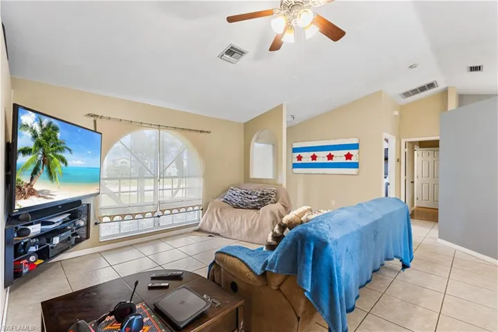 Tiled living room with ceiling fan and vaulted ceiling