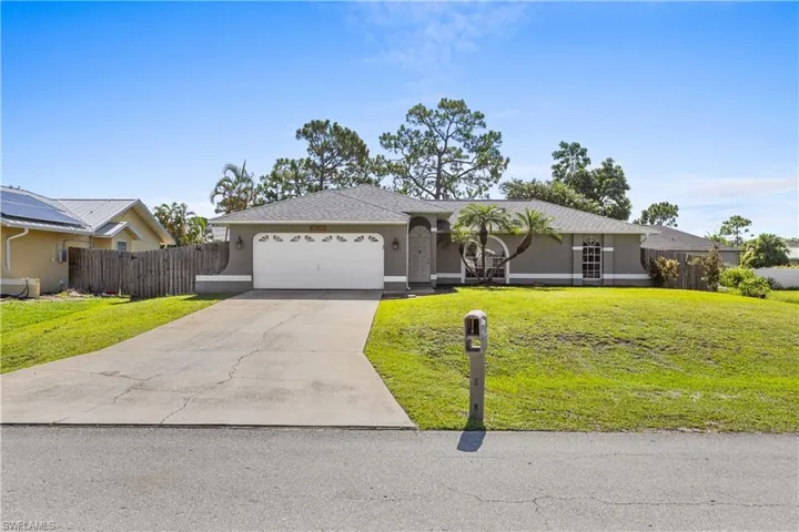 Ranch-style home featuring a garage, a front lawn, and solar panels
