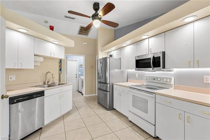 Kitchen featuring ceiling fan, stainless steel appliances, white cabinets, sink, and independent washer and dryer