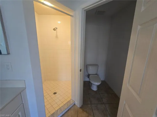 Full bathroom with a stall shower, dark tile patterned flooring, and vanity