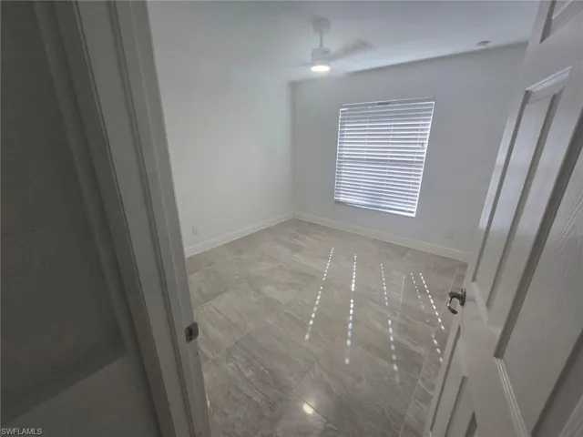 Empty room featuring ceiling fan and light marble finish floors