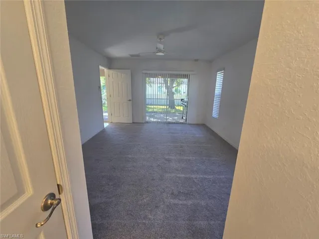 Carpeted spare room with a textured wall and a ceiling fan