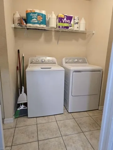 Laundry area with washing machine and clothes dryer and light tile patterned floors