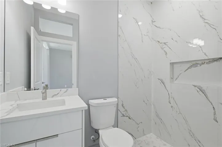 Full bath featuring vanity and a marble finish shower