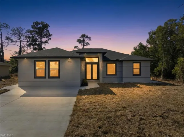 View of front facade featuring driveway, a front yard, and a shingled roof