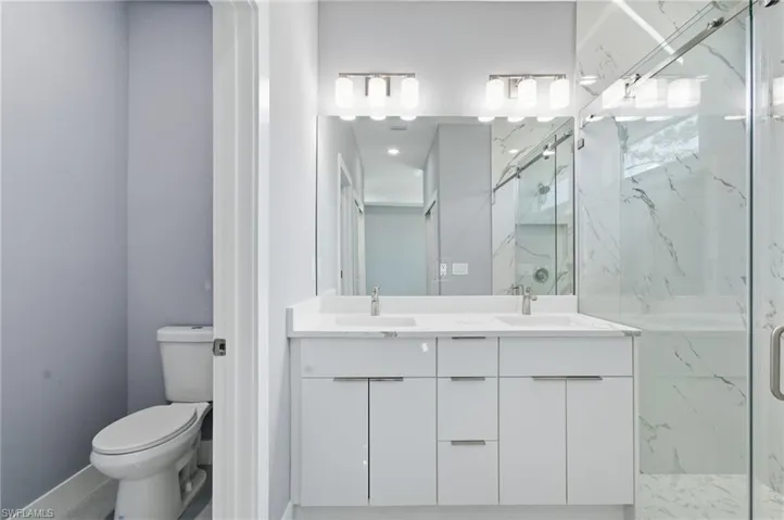 Bathroom with double vanity and a marble finish shower