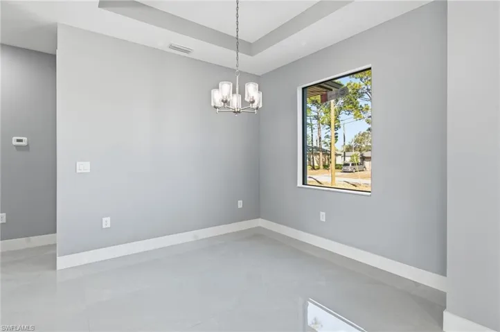 Unfurnished room with a raised ceiling and suspended lighting