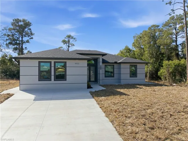 View of front of house featuring roof with shingles and driveway