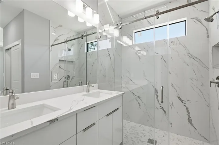 Bathroom featuring a marble finish shower and double vanity