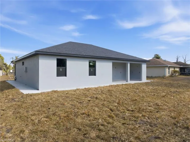 Back of property featuring a patio, stucco siding, a yard, and a shingled roof