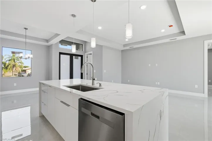 Kitchen with a tray ceiling, white cabinetry, modern cabinets, light stone countertops, and stainless steel dishwasher
