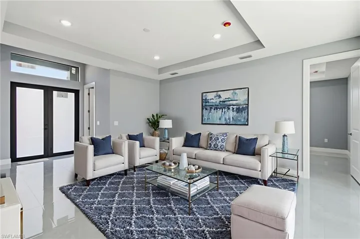 Living area featuring light tile patterned floors, recessed lighting, a raised ceiling, and french doors