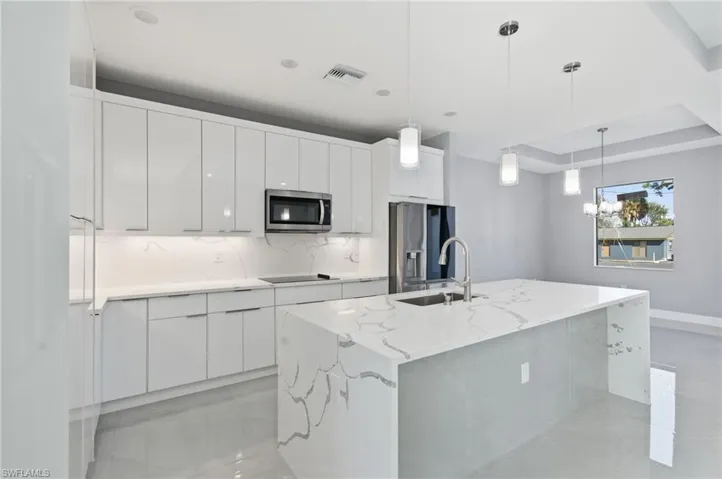 Kitchen featuring white cabinets, stainless steel appliances, modern cabinets, backsplash, and light stone counters