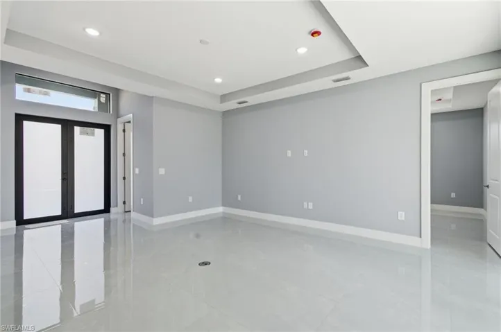 Empty room featuring recessed lighting, french doors, and a tray ceiling
