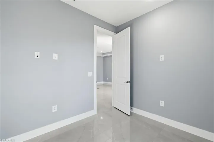 Spare room featuring baseboards and light marble finish floors