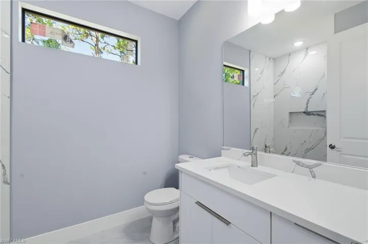 Bathroom featuring vanity and a marble finish shower