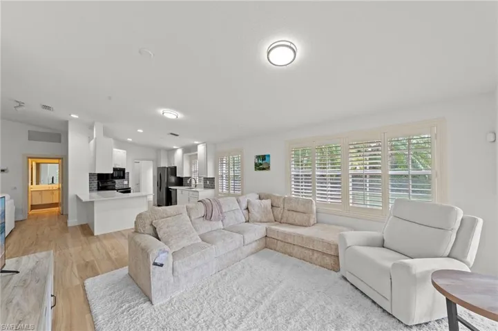 Living area featuring vaulted ceiling, light wood-style flooring, and recessed lighting