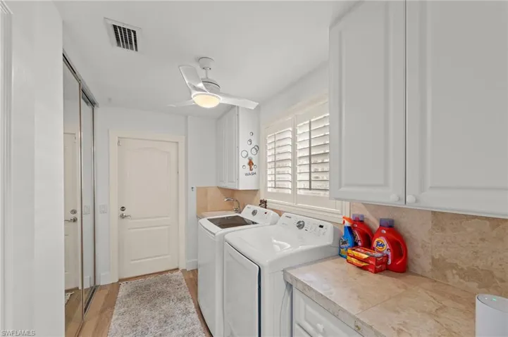 Laundry area featuring cabinet space, washing machine and dryer, light wood-style flooring, and ceiling fan