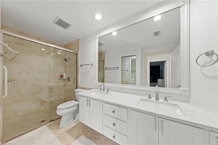 Bathroom featuring double vanity, a shower stall, and recessed lighting