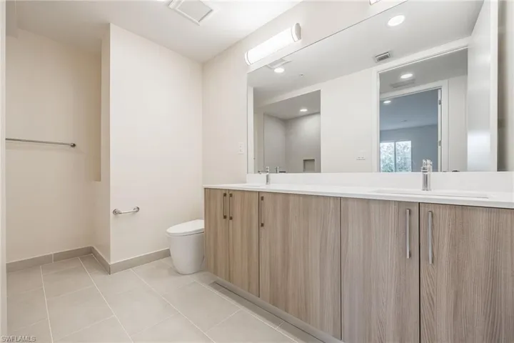 Full bath featuring double vanity, visible vents, toilet, and a sink
