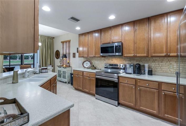 Kitchen with 1 year old appliances, wood cabinets, hard surface counters and tiled backsplash