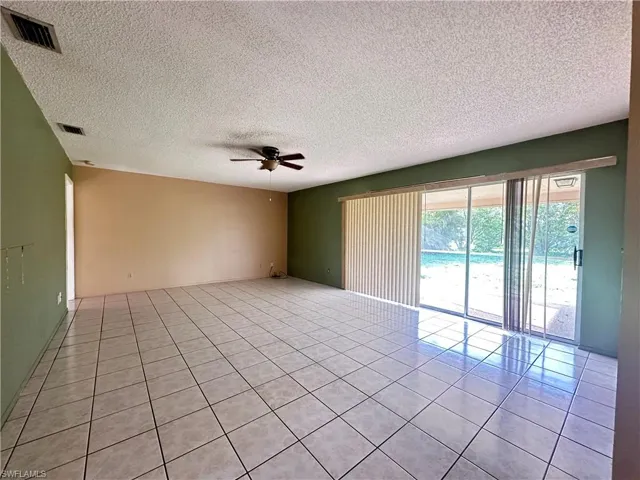 Spare room with a ceiling fan, light tile patterned floors, and a textured ceiling