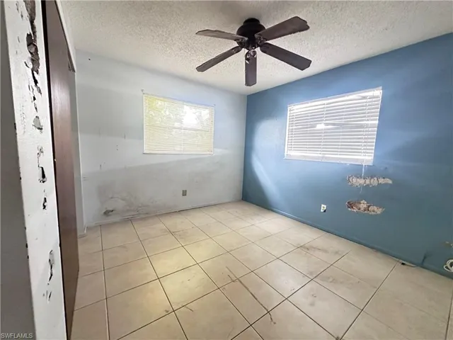Tiled empty room featuring a textured ceiling and a ceiling fan