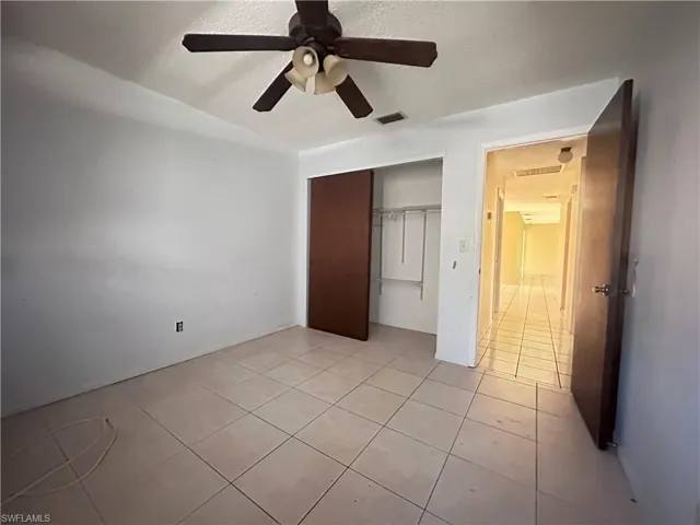 Unfurnished bedroom featuring a closet, light tile patterned floors, and a ceiling fan