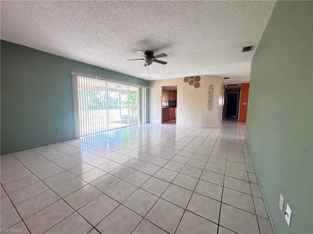 Unfurnished room featuring light tile patterned floors, ceiling fan, and a textured ceiling