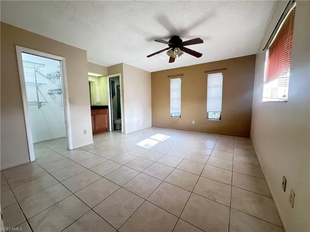 Spare room featuring a textured ceiling, ceiling fan, light tile patterned floors, and baseboards