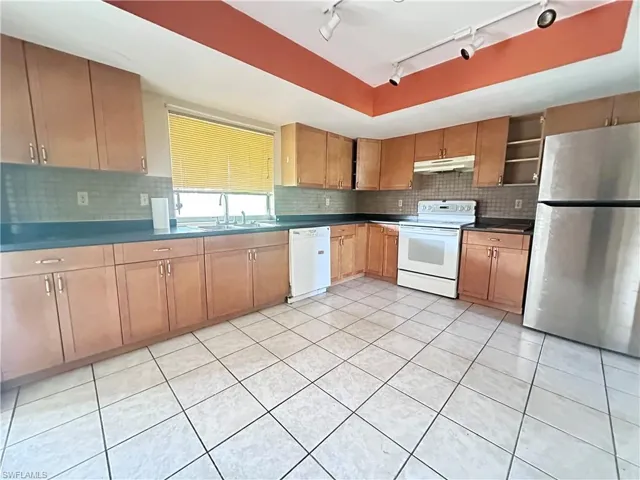 Kitchen featuring white appliances, a sink, track lighting, and light tile patterned floors