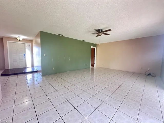 Spare room with light tile patterned floors, a ceiling fan, and a textured ceiling