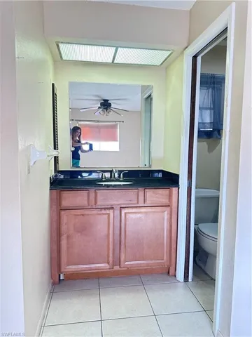 Bathroom with toilet, vanity, tile patterned floors, and ceiling fan