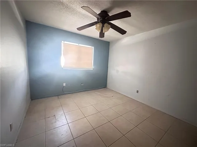 Spare room featuring ceiling fan, tile patterned floors, and a textured ceiling