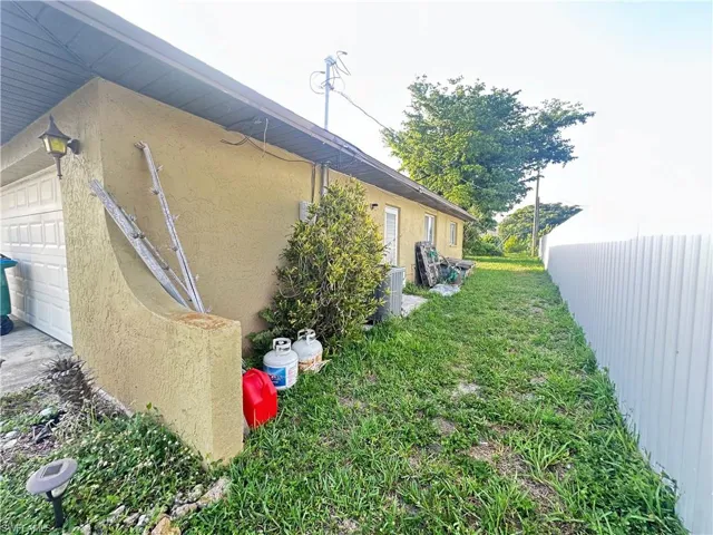 View of side of home with stucco siding, a garage, and central AC unit