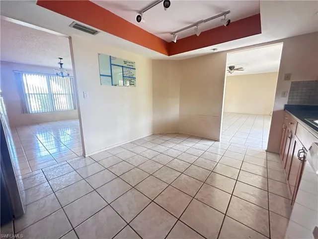 Empty room with track lighting, light tile patterned floors, and a chandelier