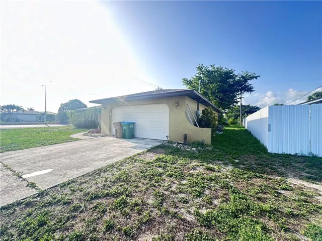 View of side of property featuring stucco siding, a garage, and concrete driveway