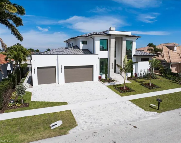 Contemporary home featuring a standing seam roof, a garage, a front yard, decorative driveway, and stucco siding