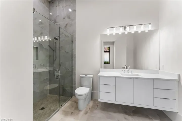 Full bath featuring vanity and a marble finish shower