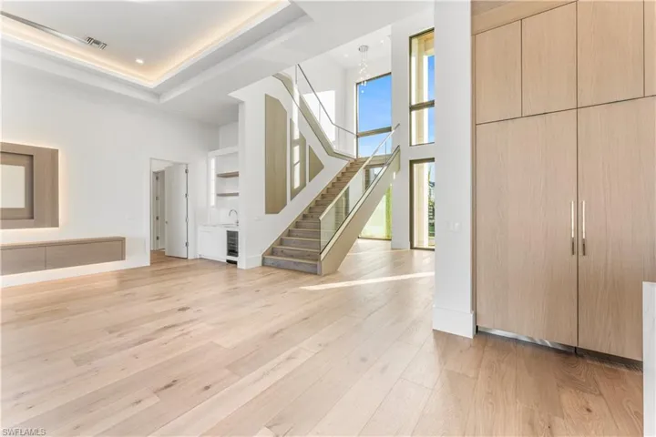 Foyer featuring a high ceiling, light wood-style flooring, beverage cooler, and recessed lighting