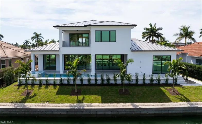 Modern home with a standing seam roof, a garage, decorative driveway, and a front yard