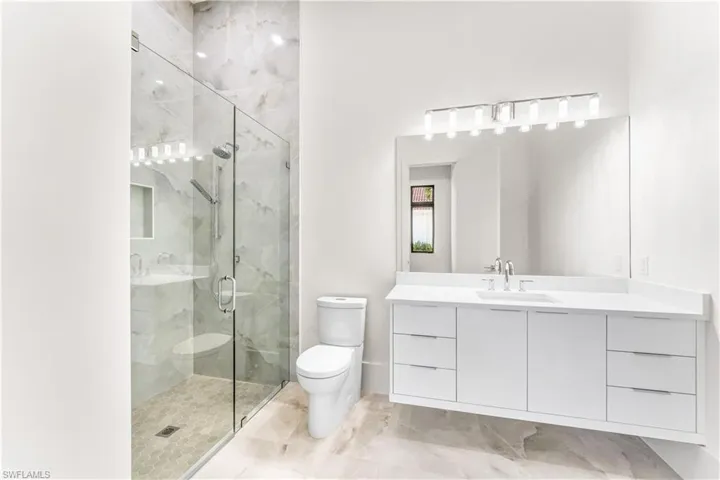 Bathroom featuring vanity and a marble finish shower
