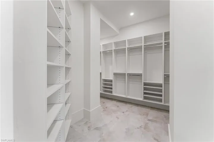 Walk in closet with light marble finish flooring